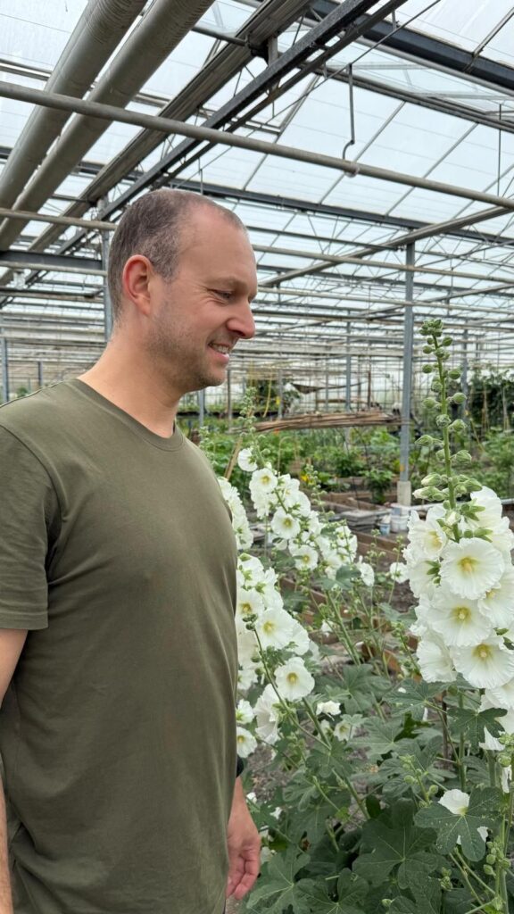 Thomas van Emmerik van SIL-HR in zijn moestuin tussen de stokrozen